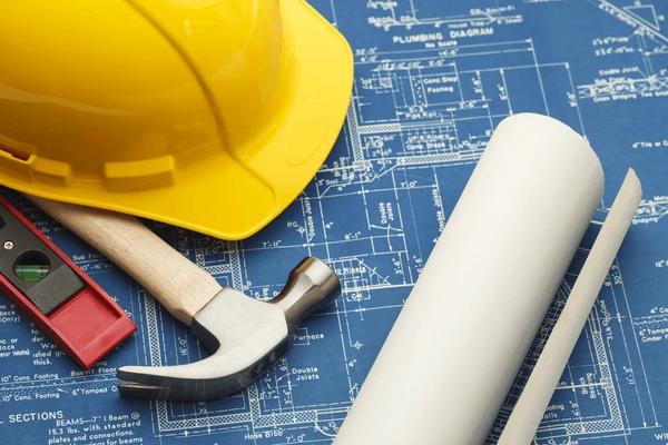 Blueprint and hard hat symbolizing building a strong foundation before real estate investing